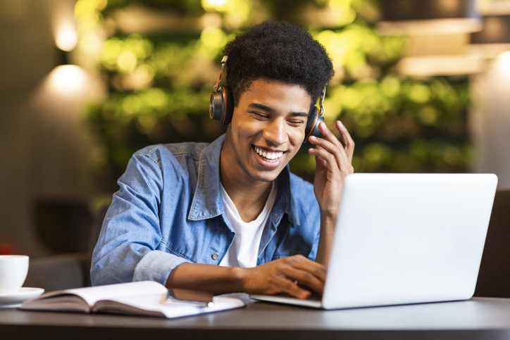 A student wearing headphones while making music on a laptop