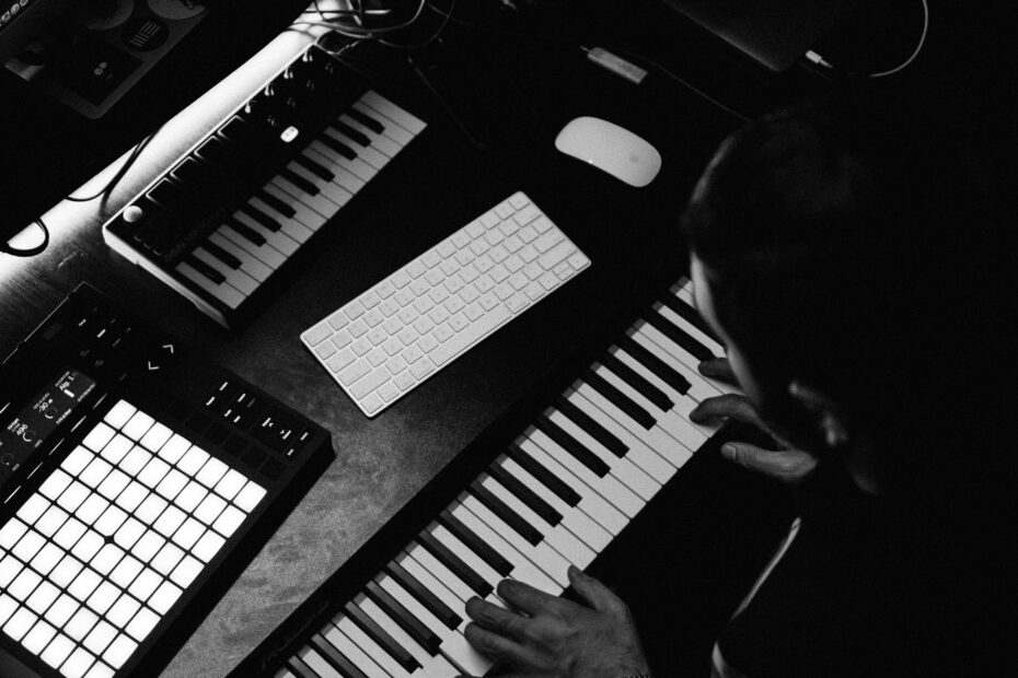 A musician collaborating at a keyboard and music production workstation